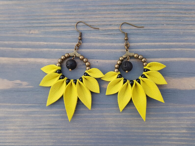 May include: A pair of yellow leather earrings with black beads and a black lava rock bead in the center of each earring.