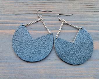 Peut inclure: Une paire de boucles d'oreilles en cuir bleu foncé avec une forme géométrique et des accents de chaîne argentée.