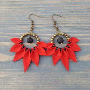 May include: Red leather earrings with black beads and a lava rock accent. The earrings are in the shape of a flower with multiple petals.
