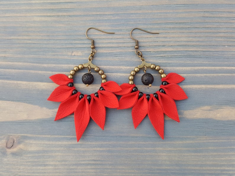 May include: Red leather earrings with black beads and a lava rock accent. The earrings are in the shape of a flower with multiple petals.