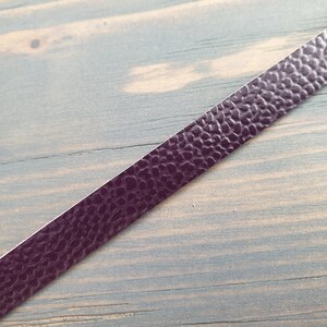 May include: A close-up of a dark purple leather strip with a textured surface.
