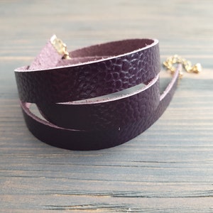 May include: A purple leather choker necklace with a gold clasp.