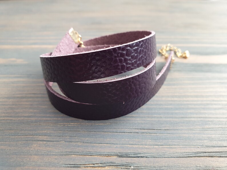 May include: A purple leather choker necklace with a gold clasp.