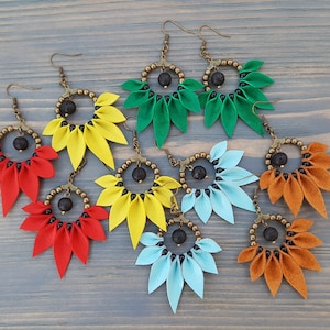 May include: Six pairs of earrings with a flower-shaped design. Each pair features a different color: green, yellow, red, blue, and orange. The earrings are made with leather and have a black lava rock bead in the center.