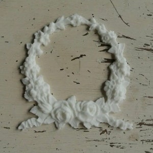 May include: White floral wreath with a circular design and a bow at the bottom. The wreath is made of a lightweight material and is perfect for adding a touch of elegance to any home decor.