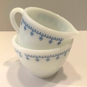 K&ouml;nnte beinhalten: Zwei wei&szlig;e Keramik-Sch&uuml;sseln mit blauen Schneeflocken-Designs. Die Sch&uuml;sseln sind ineinander verschachtelt.