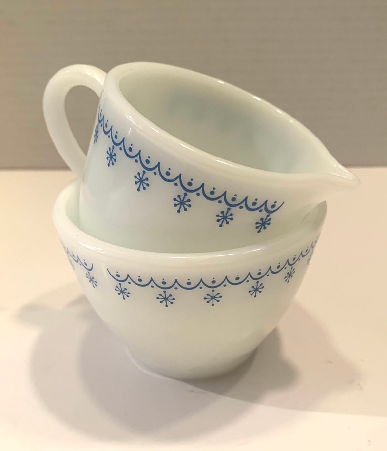 K&ouml;nnte beinhalten: Zwei wei&szlig;e Keramik-Sch&uuml;sseln mit blauen Schneeflocken-Designs. Die Sch&uuml;sseln sind ineinander verschachtelt.