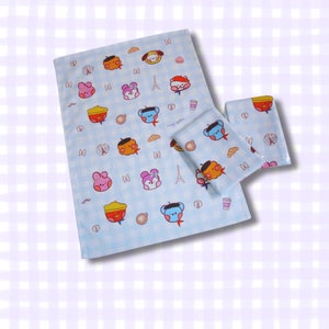 May include: Light blue and white checkered bedding set featuring cartoon characters, croissants, coffee cups, and Eiffel Tower illustrations. The set includes a large blanket and two smaller pillowcases.