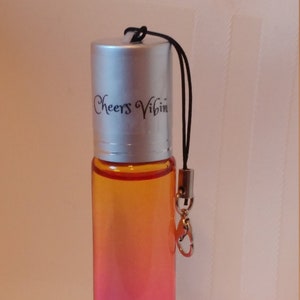 May include: A small, silver, roll-on bottle with a black lanyard and a silver clasp. The bottle is filled with a pink and orange liquid. The bottle has the text "Cheers Vibin'" printed on the side.