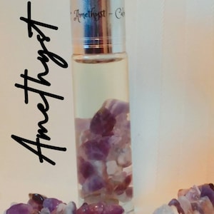 May include: A clear glass roller bottle with a silver lid and amethyst crystals inside. The label on the bottle reads "Amethyst - Calm".