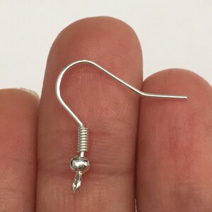 May include: Silver earring hook with a small ball at the end. The hook is made of metal and has a spring-loaded closure.