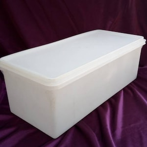 May include: A white plastic storage container with a lid. The container is rectangular and has a smooth surface.