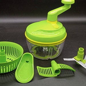 May include: A green and clear manual food chopper with a hand crank, blades, and a basket. The chopper has a clear container with a green lid and a yellow accent. Additional green accessories are included.