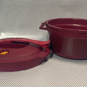 May include: A burgundy pressure cooker with a lid and a handle. The lid has a yellow valve.