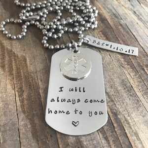 May include: Silver necklace with a dog tag pendant that says "I will always come home to you" with a heart symbol. The dog tag also has a small round charm with a medical symbol. The necklace has a small tag with the text "B&S ♥ 1.10.17".