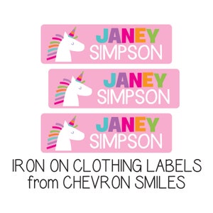 May include: Three pink iron-on clothing labels with a white unicorn and the name "JANEY SIMPSON" in colorful letters. The labels are for clothing and are from CHEVRON SMILES.