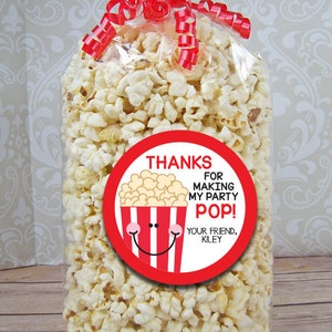 May include: A red and white popcorn party favor bag with a round sticker that says "Thanks for making my party pop! Your friend, Kiley".