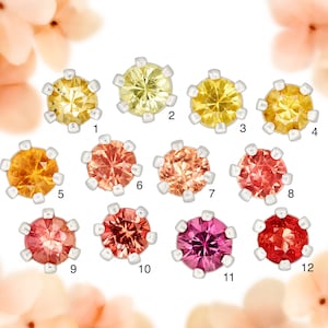 May include: Twelve round gemstones with silver settings, ranging in color from yellow to orange to red. The gemstones are numbered 1 through 12.