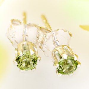 May include: A pair of silver stud earrings with green gemstones. The earrings have a simple, elegant design.