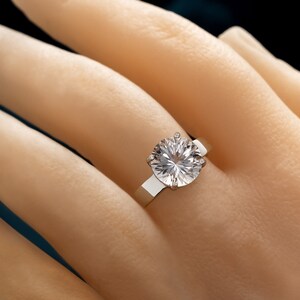 May include: A silver ring with a large, round, clear diamond.