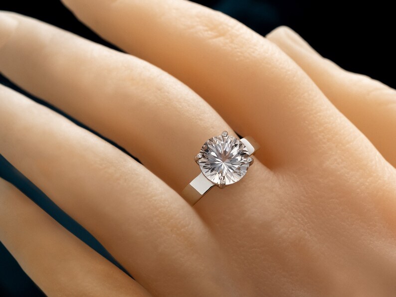 May include: A silver ring with a large, round, clear diamond.