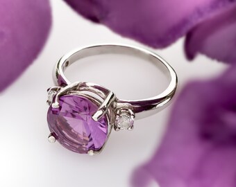 May include: A silver ring with a large, oval-shaped amethyst gemstone and two smaller diamond accents.