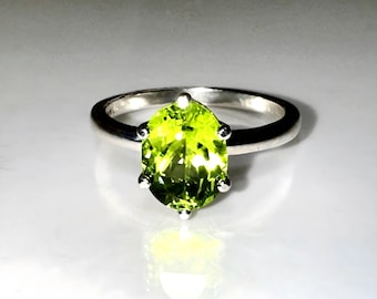 May include: A silver ring with a large, oval-shaped, green peridot gemstone.