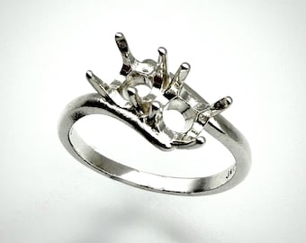 May include: A silver ring setting with prongs designed to hold two gemstones. The ring has a curved band and a detailed setting, perfect for jewelry making or custom designs. The ring is shown against a white background.