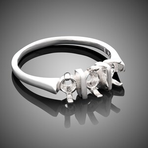 May include: A silver ring with five prongs for setting stones. The ring is designed to hold a center stone and two smaller stones on either side.