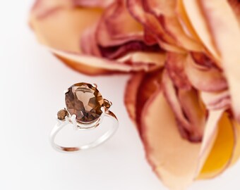May include: A silver ring with a large oval-shaped brown gemstone and two smaller brown gemstones on the sides.