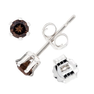 May include: A pair of silver stud earrings with brown gemstone accents. The earrings have a post and butterfly back.