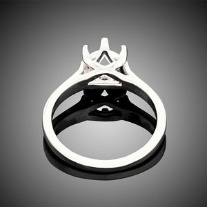 May include: A silver ring setting with a prong setting for a center stone. The setting has a delicate, intricate design.