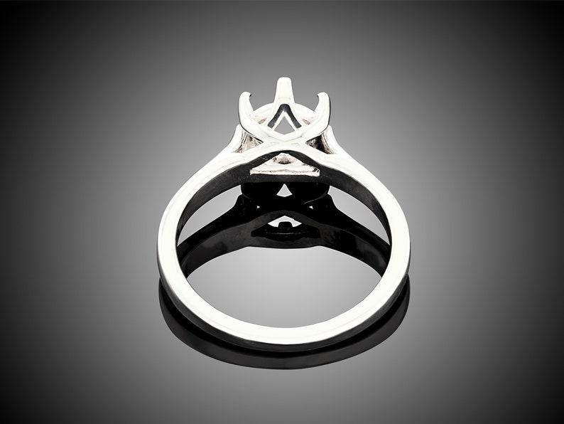 May include: A silver ring setting with a prong setting for a center stone. The setting has a delicate, intricate design.