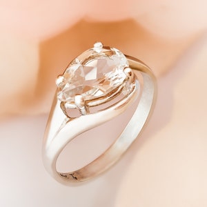 Puede incluir: Un anillo de plata con una piedra preciosa transparente en forma de pera engastada en un diseño delicado e intrincado.