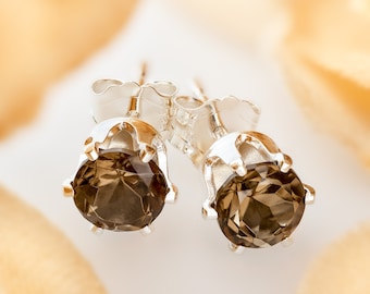 May include: A pair of silver stud earrings with round, faceted, smoky quartz gemstones.