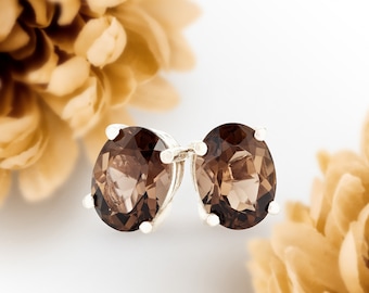 May include: A pair of silver stud earrings with oval-shaped smoky quartz gemstones.