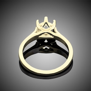 May include: A gold ring setting with a prong setting for a center stone. The setting is designed with a delicate, intricate pattern.