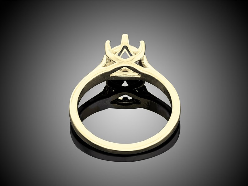 May include: A gold ring setting with a prong setting for a center stone. The setting is designed with a delicate, intricate pattern.