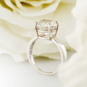 May include: A silver ring with a large, clear, round diamond set in a cage-like setting.