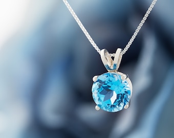 May include: A silver chain necklace with a round, light blue topaz pendant.