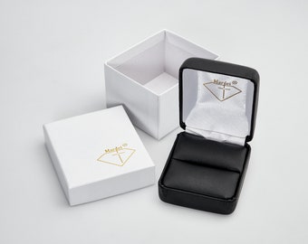 May include: A white ring box with a black velvet interior and the text "Marlei®" in gold lettering. The box is open and the velvet interior is visible.