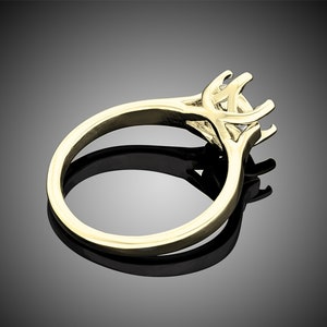 May include: A gold ring with a prong setting for a center stone. The ring is designed with a delicate, intricate band.