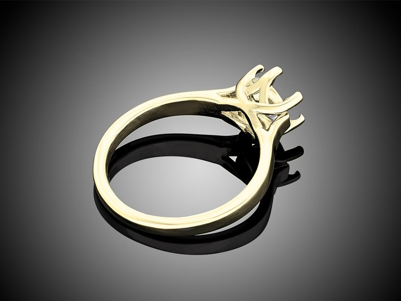 May include: A gold ring with a prong setting for a center stone. The ring is designed with a delicate, intricate band.
