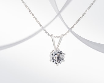 May include: A silver chain necklace with a clear, faceted gemstone pendant.
