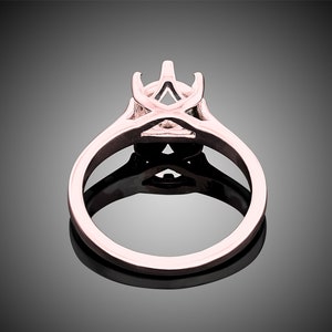 May include: A rose gold engagement ring setting with a delicate, open-work design. The setting is designed to hold a center stone, with prongs to secure it in place.