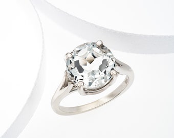 May include: A silver ring with a large, clear, round gemstone set in a prong setting.