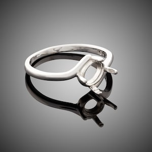 May include: A silver ring with a blank oval setting. The ring is designed to hold a gemstone.