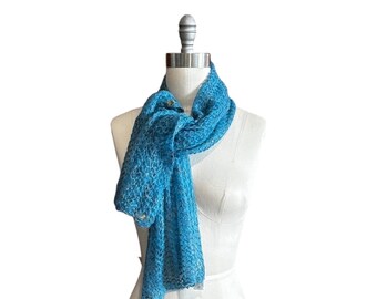 Peut inclure: Une écharpe bleu turquoise vif présentant un motif en dentelle ajourée complexe. L'écharpe est drapée autour du cou d'un mannequin blanc, mettant en valeur sa texture légère et semi-transparente ainsi que son motif géométrique délicat.