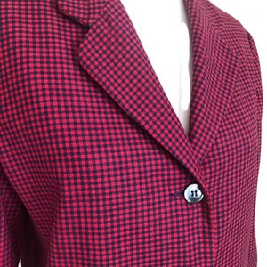 May include: A red and black gingham blazer with a notched collar and three buttons. The blazer is made of a woven fabric.