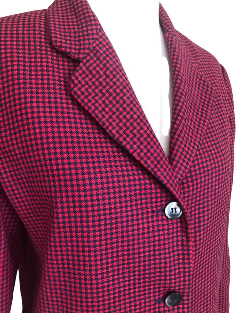 May include: A red and black gingham blazer with a notched collar and three buttons. The blazer is made of a woven fabric.